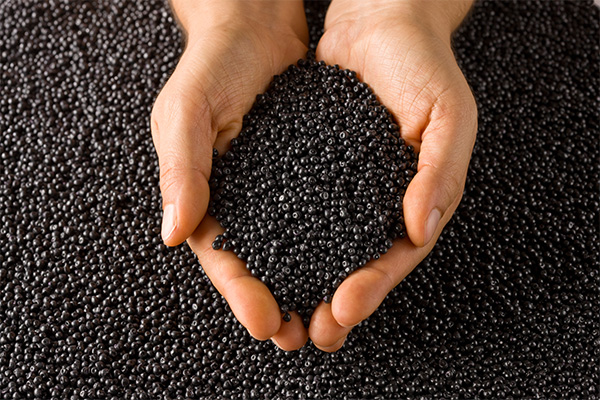 Two hands full of black LUCOBIT plastic granules