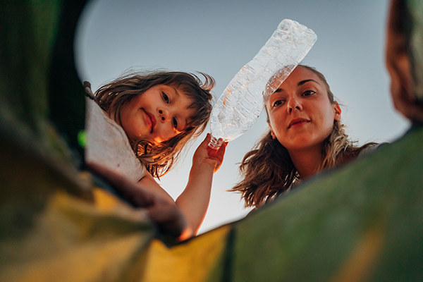 Kind wirft mit Mutter Plastikflasche in den Müll