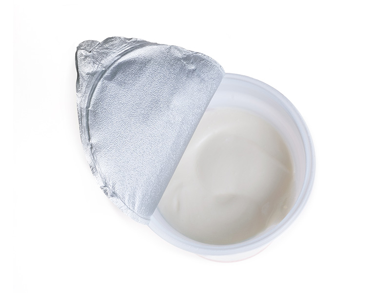 Geöffneter Joghurtbecher aus Lucofin auf weißem Hintergrund