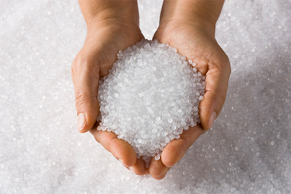 Two hands full of colorless plastic granules from Lucofin