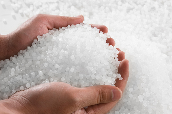 Two hands full of colorless plastic granules made of Lucofin