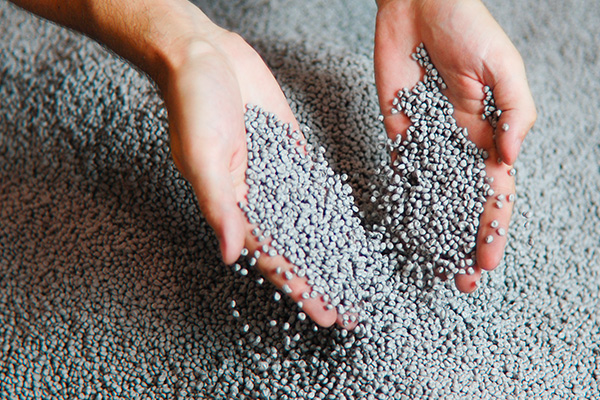 Two hands full of gray plastic granulate for civil engineering