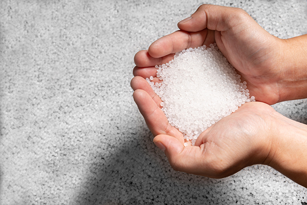 Two hands full of colorless plastic granules made from Lucofin